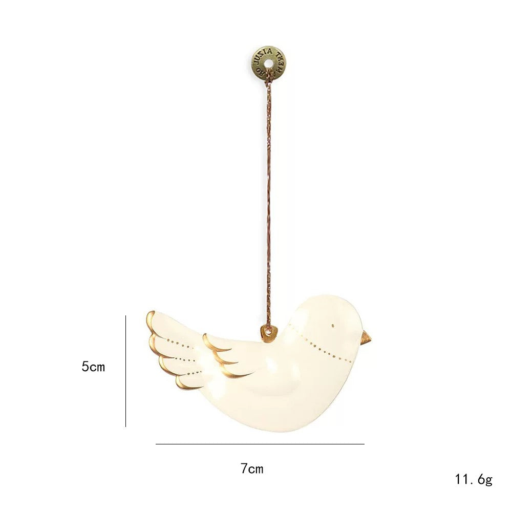A white dove Christmas ornament has a raised wing, a fan shaped tail and gold colored details at the edges.