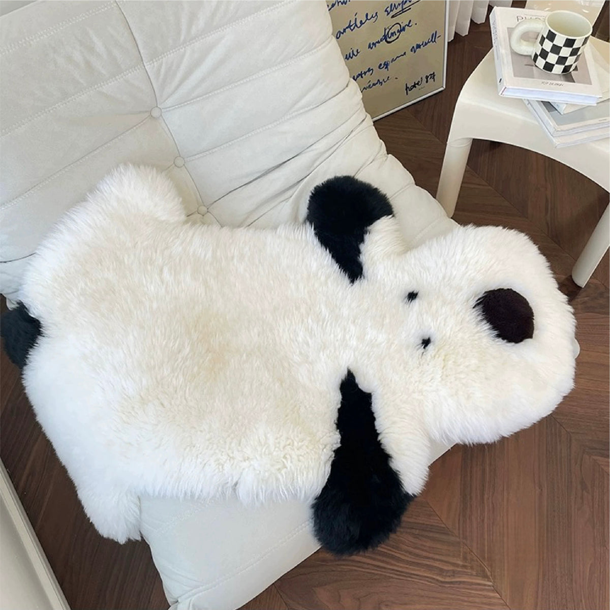 A white puppy rug rests across a chair, showing small dark eyes, a round nose and long black ears.