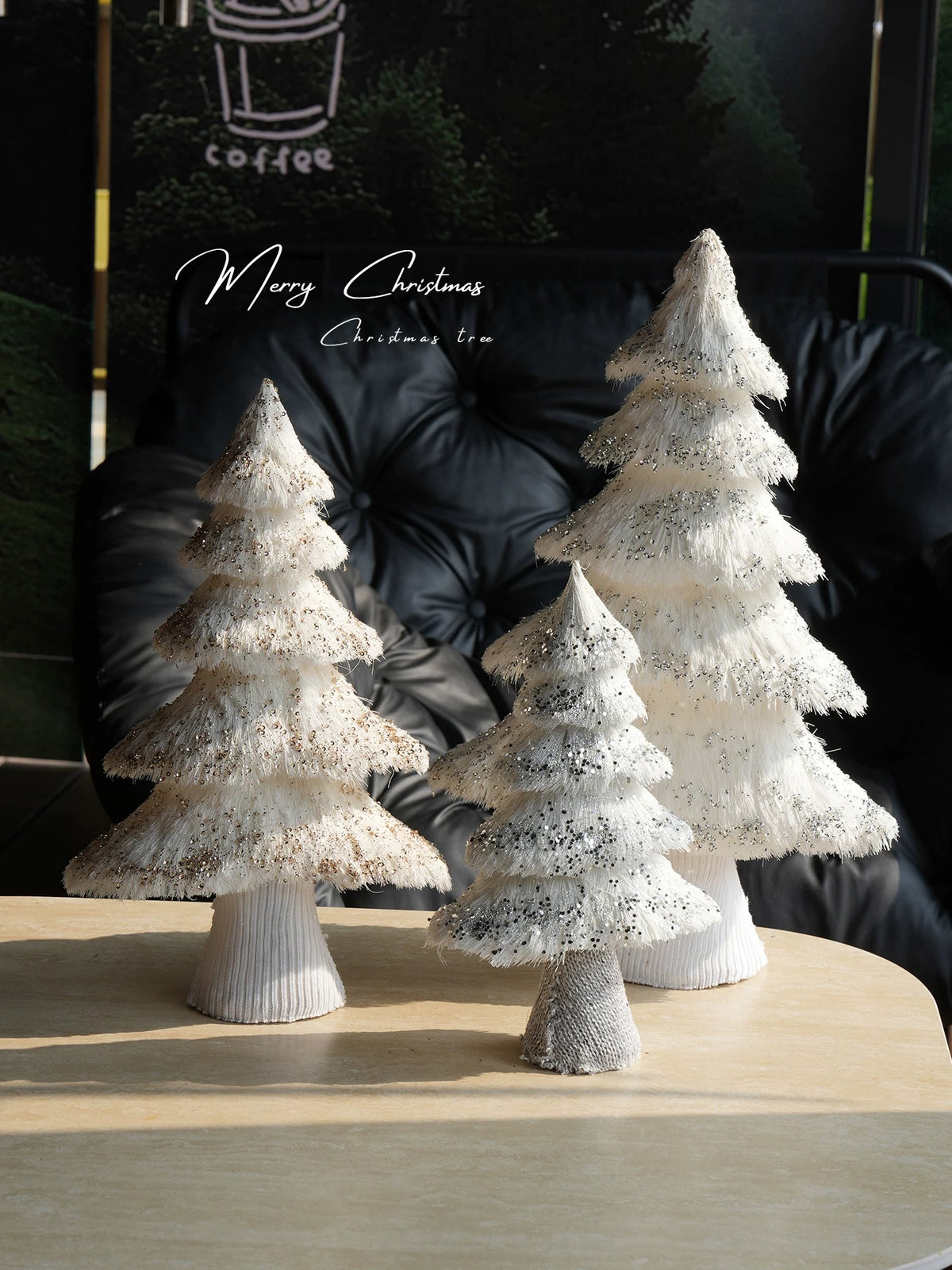 A white tabletop Christmas tree group shows pointed tops, layered branches and wrapped bases on a table.