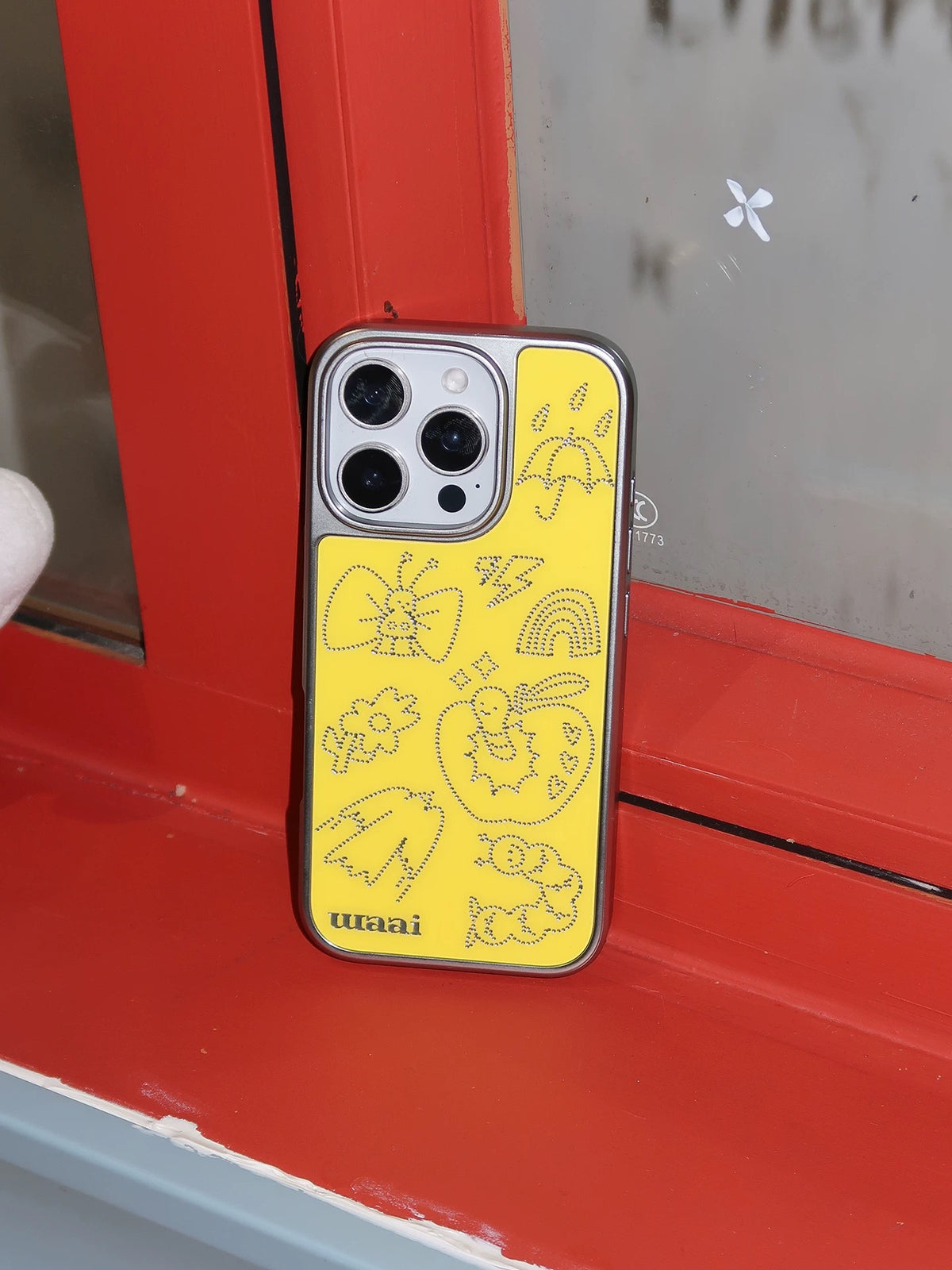 A yellow graphic phone case in a second upright view, with silver dotted illustrations across the back.