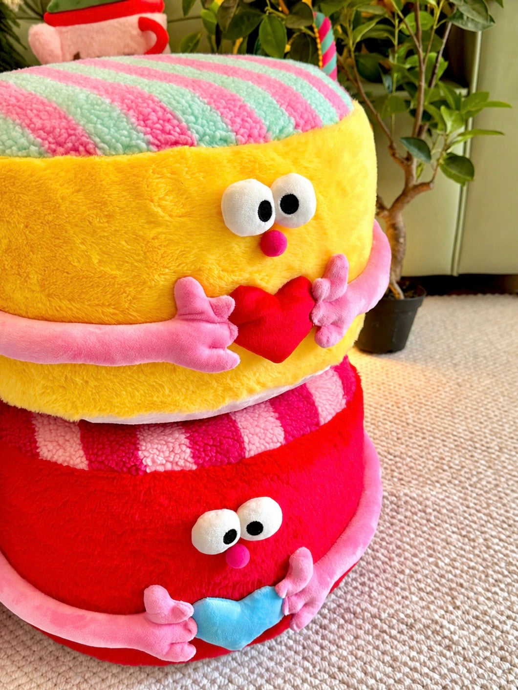 Yellow plush ottoman with striped top, pink arms, and red heart